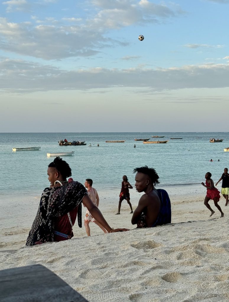 Nungwi beach - Zanzibar Maasai wearing kikois, playing football on white sand beach.